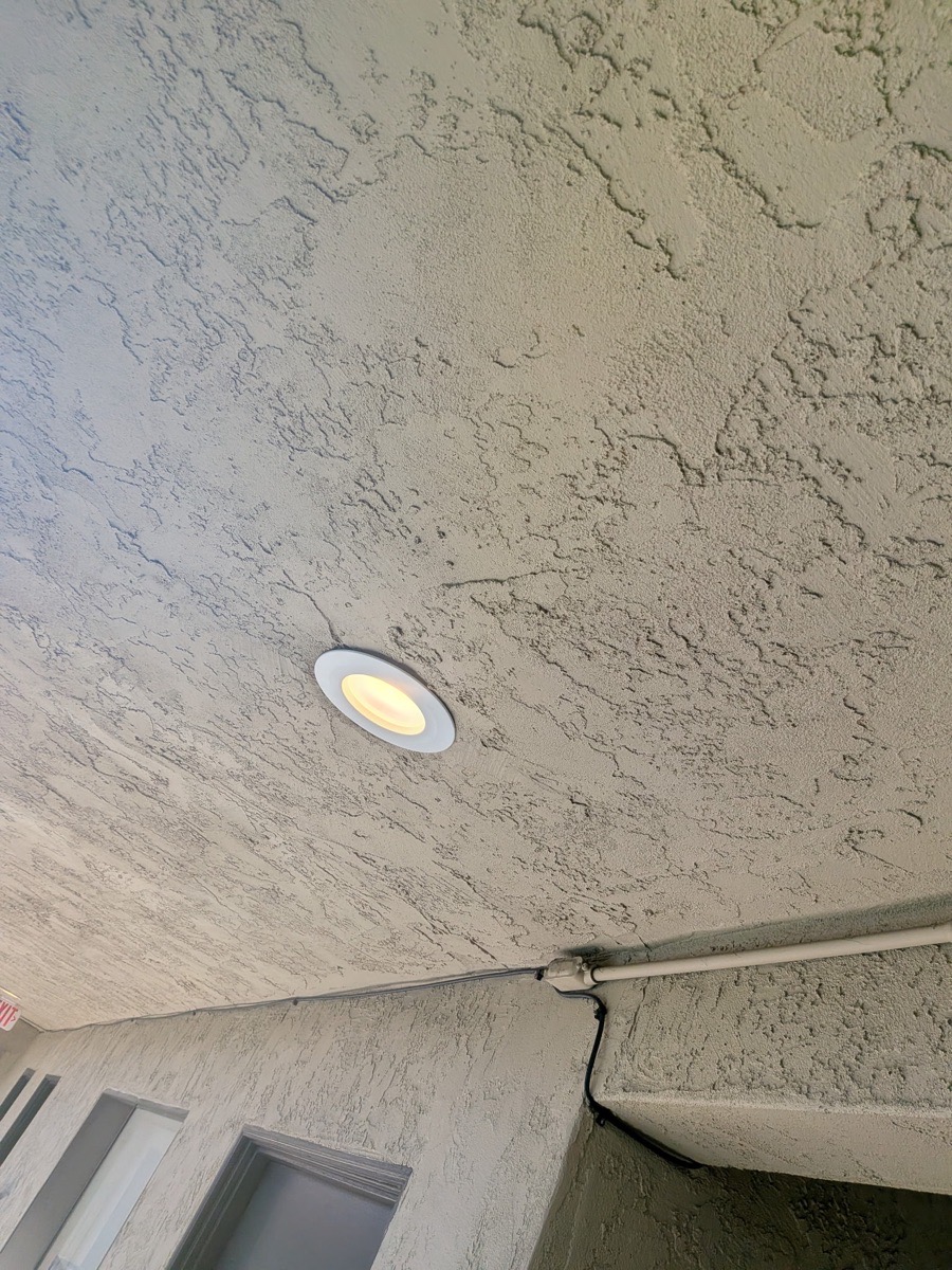Illuminated circular LED fixture installed in a textured common-area ceiling
